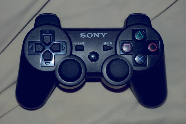 a black playstation controller sitting on top of a table