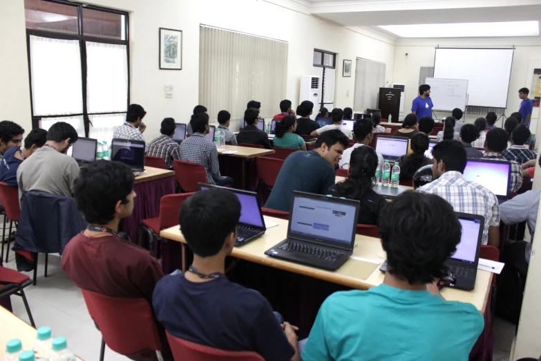 group of people on chairs with laptops on them