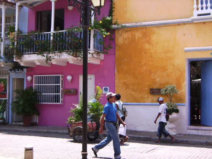 a couple walking down the street past a tall building