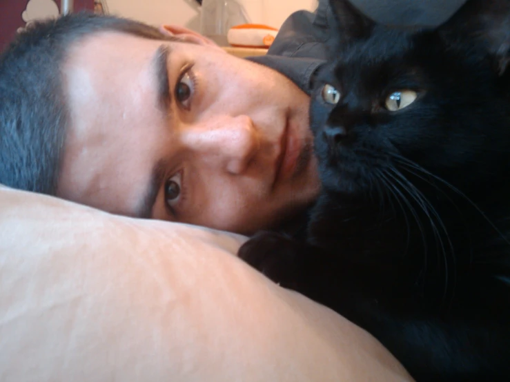 a young man laying in bed with a black cat