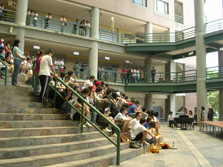 a group of people are sitting on the steps at a building