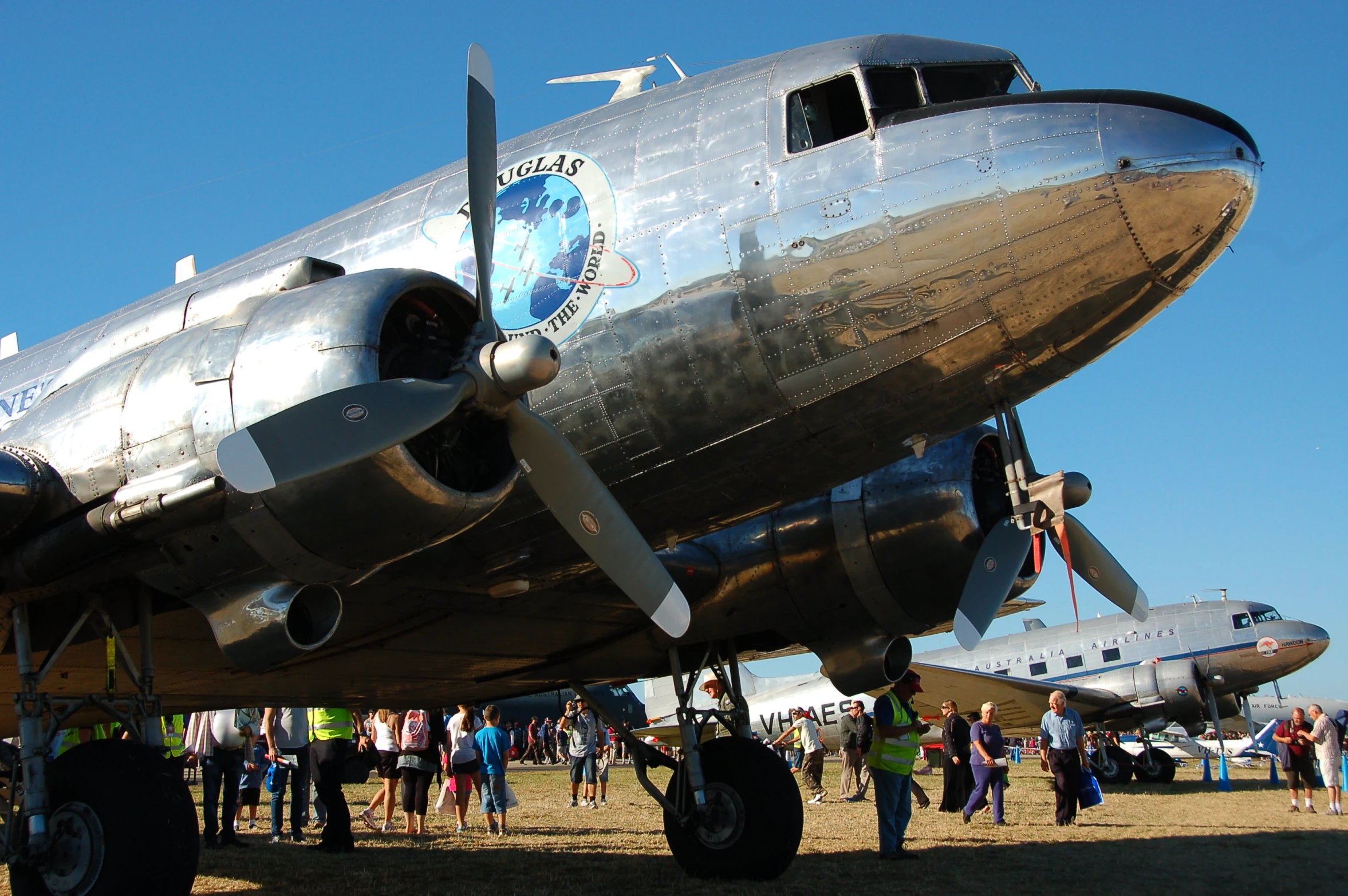 people standing next to an airplane in the grass