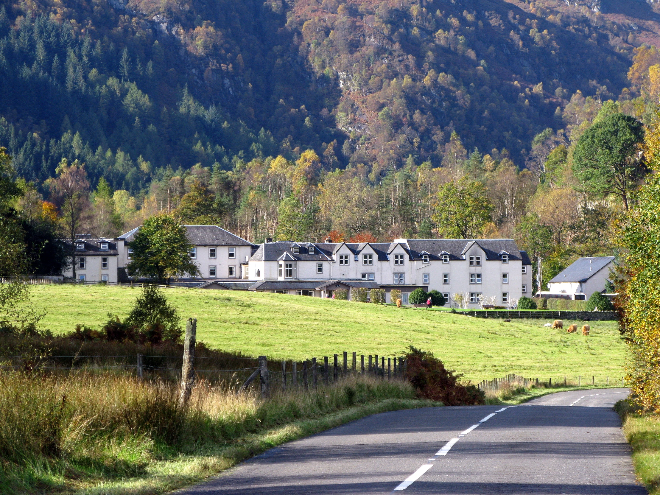 a road with a big white building sitting between mountains