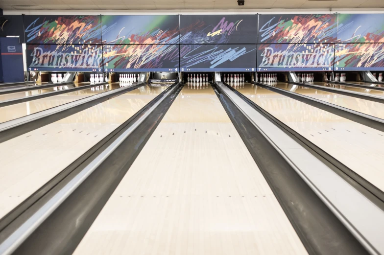 a bowling alley has a few lanes with bowling balls coming down it