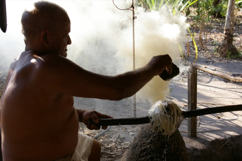 a man in tan shorts smokes fire on an outdoor fire pit