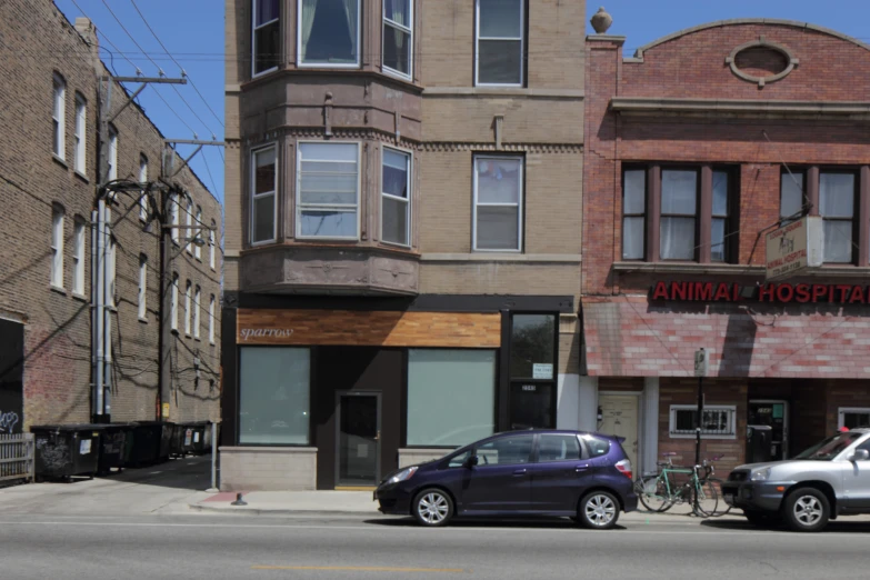 the purple car is parked at the curb by the building