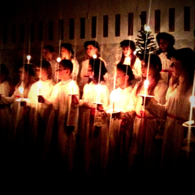 a group of young people standing next to each other holding candles