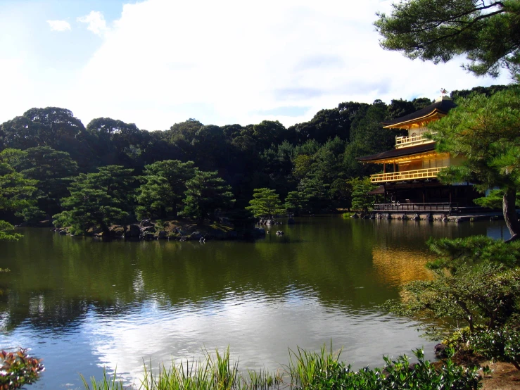 a lake surrounded by tall trees with a building in the background