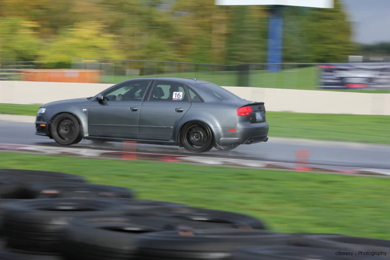 a black sedan with black rims driving on a race track
