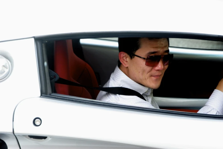 a man wearing a tie and a white shirt is driving