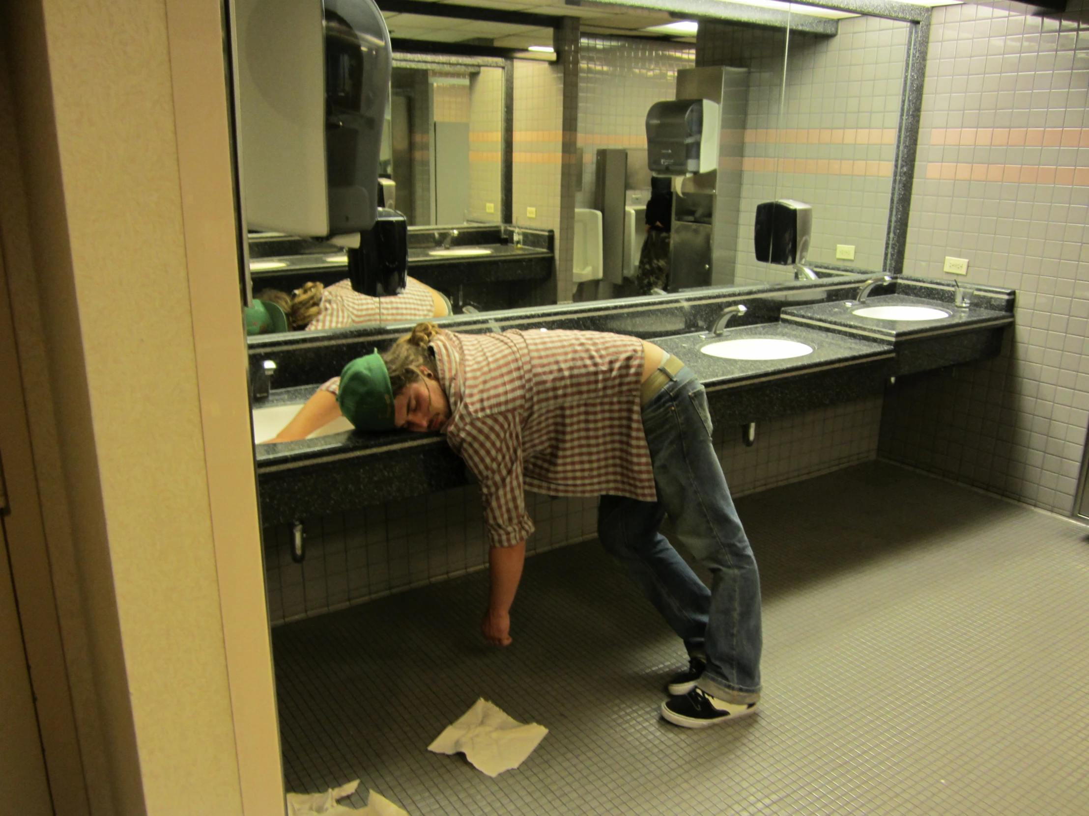 a man in plaid shirt leaning over a sink