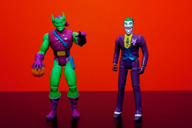 two action figures standing in front of a red background