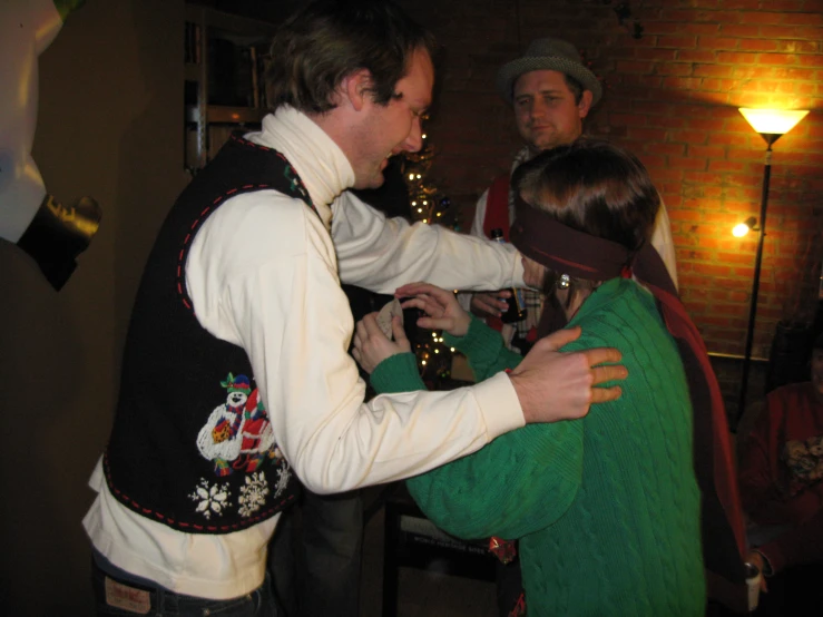 a man holding onto the back of a girl while a woman with her head wrapped in a green blanket