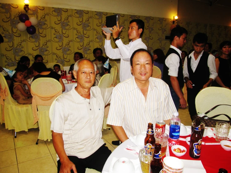 two men are sitting at tables with bottles