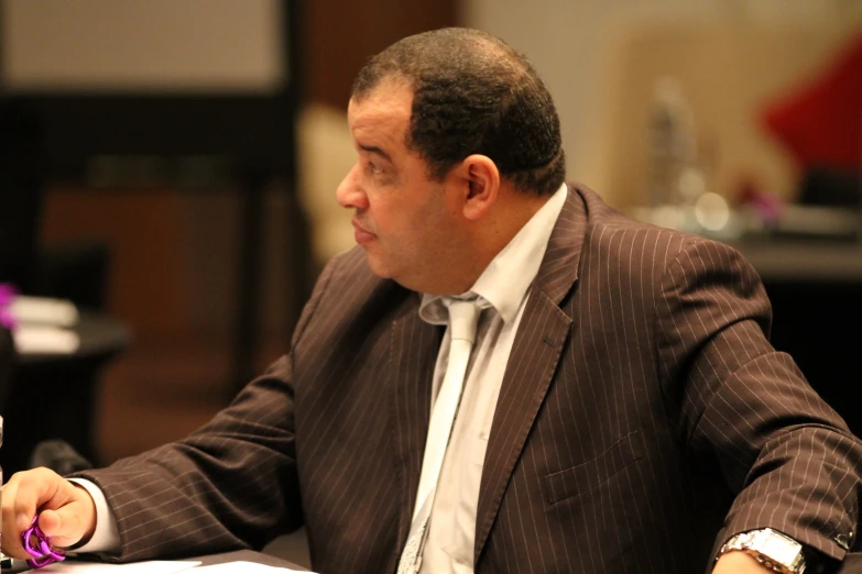 man in brown striped jacket working at desk with pen and paper