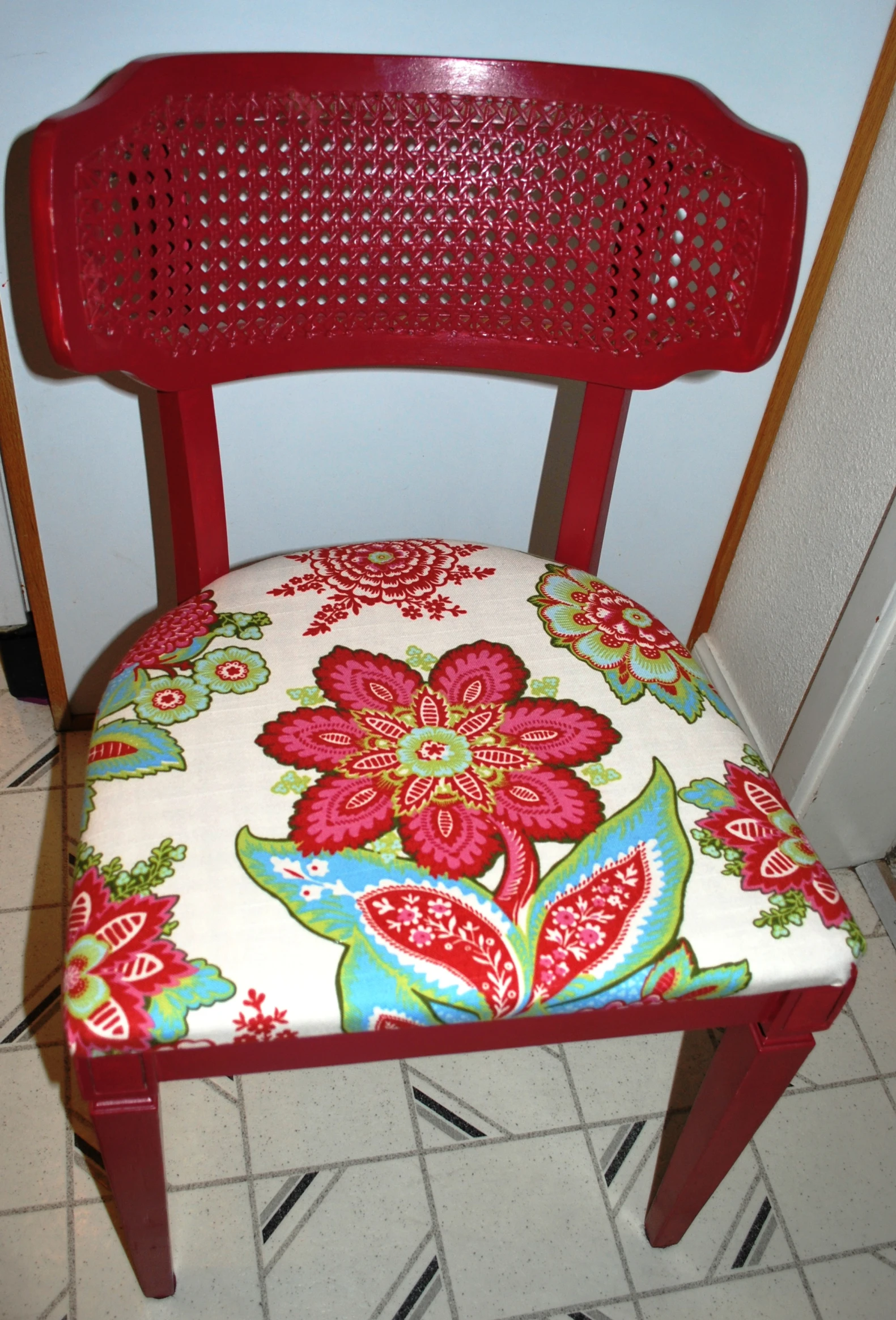 a red chair with a patterned fabric cushion sits on tile