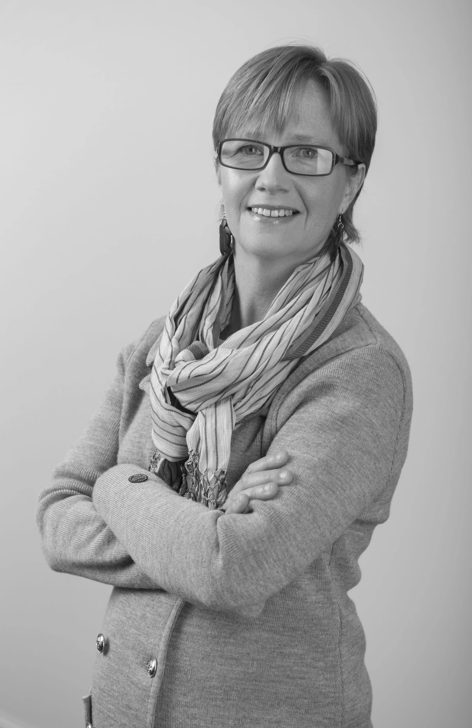 a woman with her arms crossed, wearing a scarf