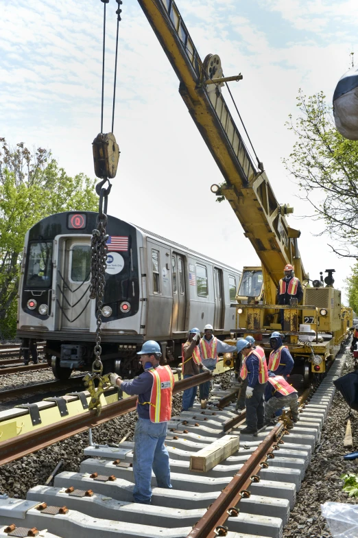 men in yellow vests and orange safety jackets standing on train tracks