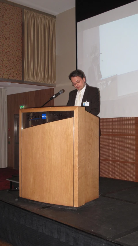 a man standing at the front of a podium holding a microphone