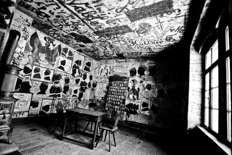 a dark room with a table, stools and a wall with graffiti all over it