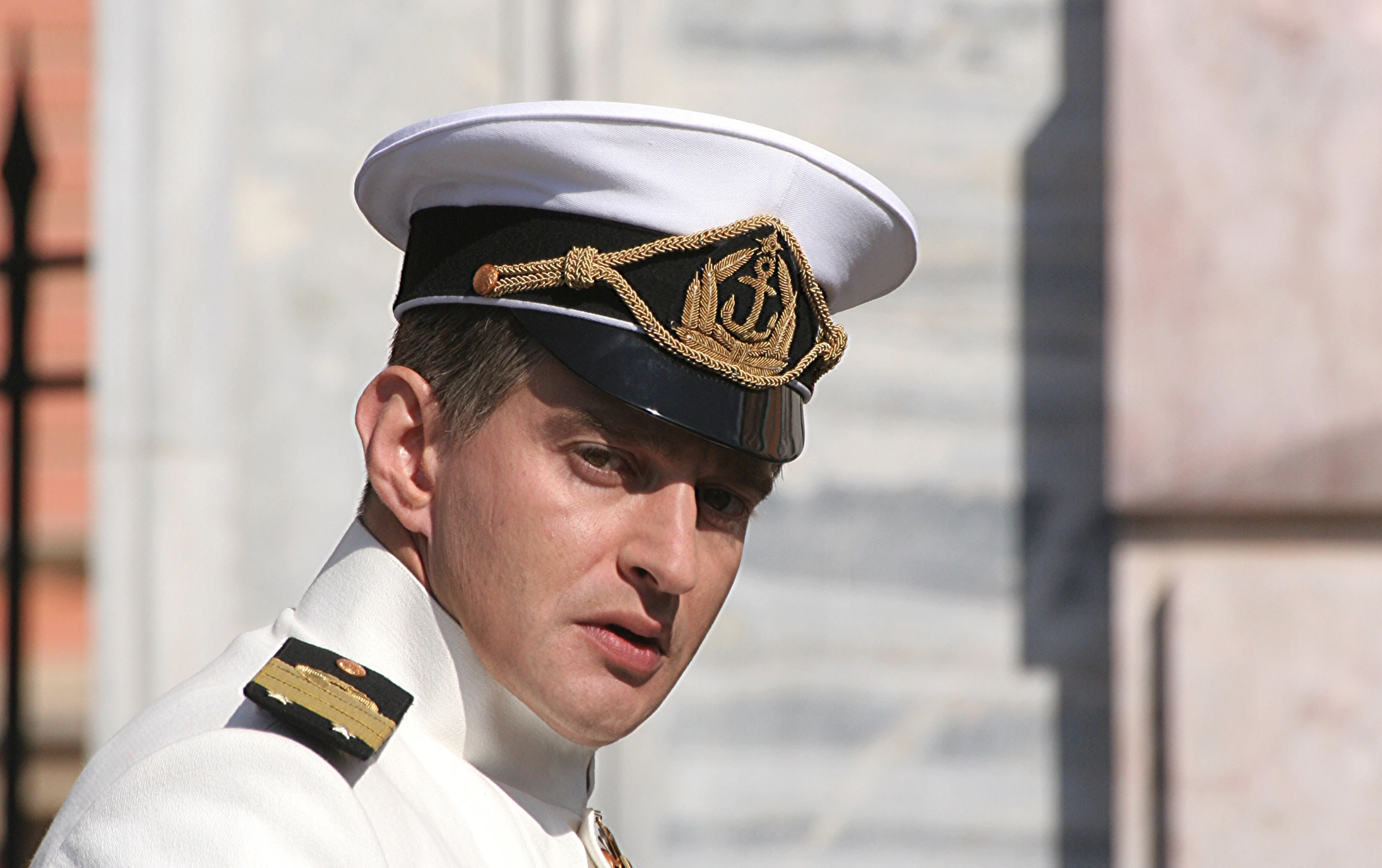 a military man wearing a white dress uniform with a black cap