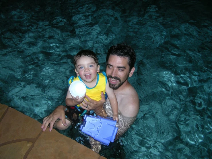 a man holding a child holding a toy in the water