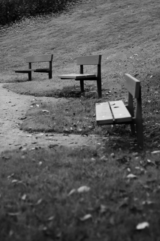 two benches are sitting outside and on the grass