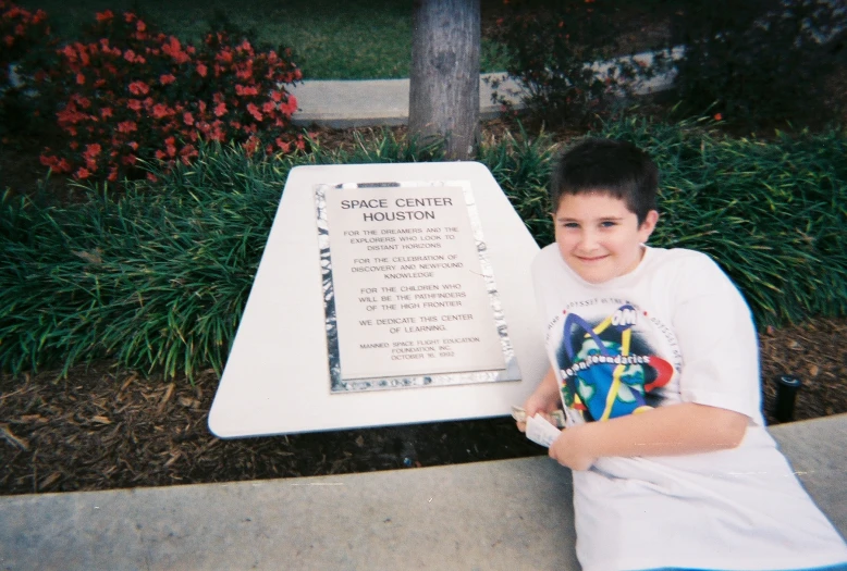the boy is sitting next to the plaque with the name of the president