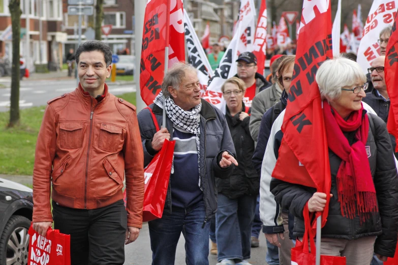 people are holding red flags and a banner on a street