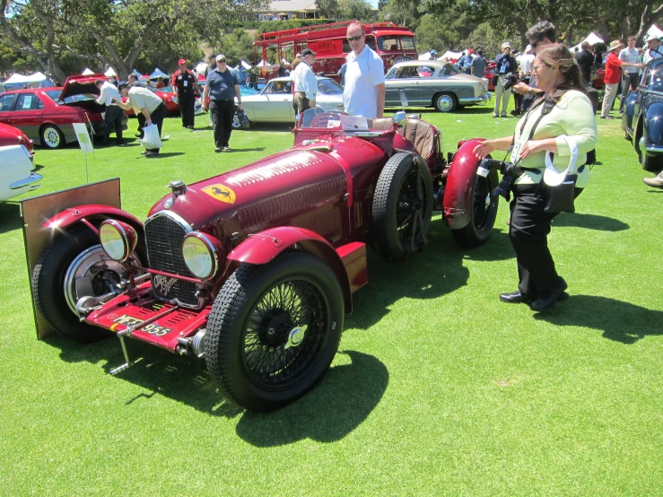 people are looking at some old cars on display