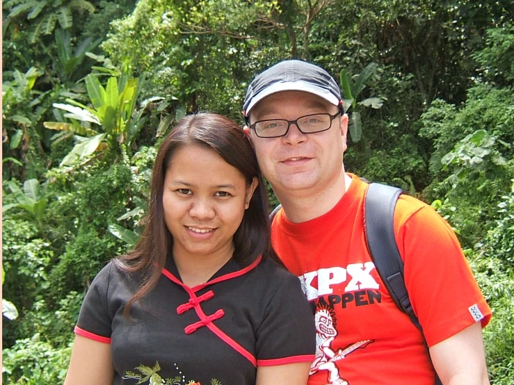 a man and woman taking a picture in front of some bushes