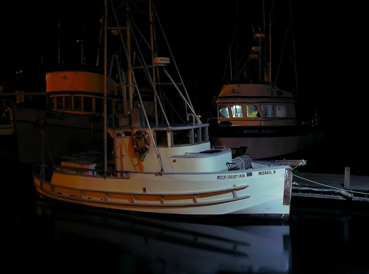 two boats are tied to a dock at night