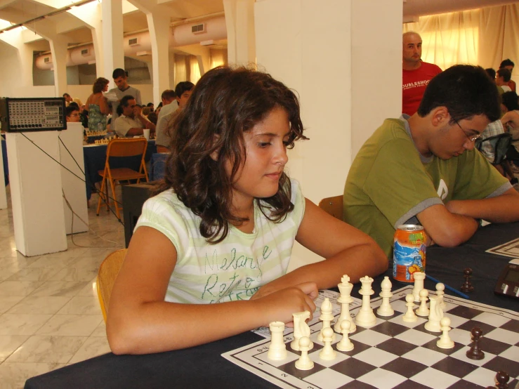 a little girl plays chess with her grandfather