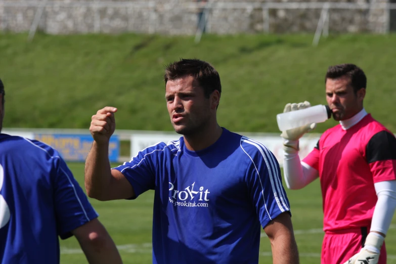 a man wearing blue is getting his face covered by another man in red