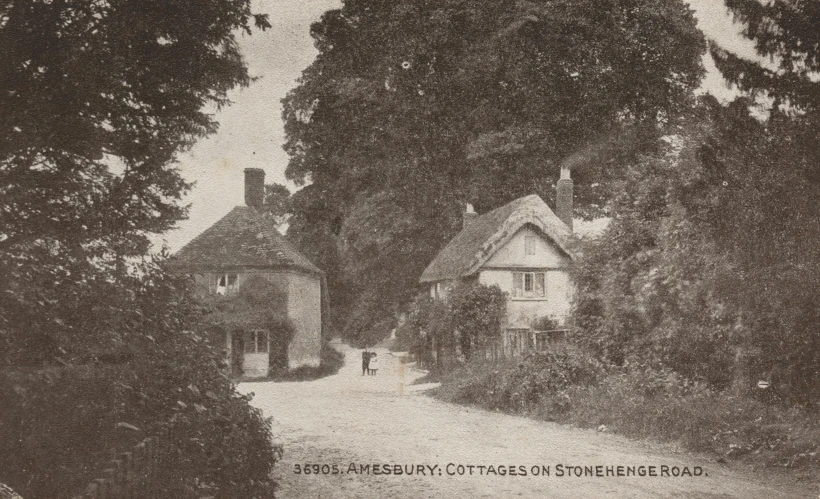 old black and white picture showing a country road near a building