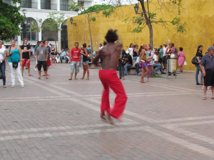 a man is dancing on a sidewalk while people watch