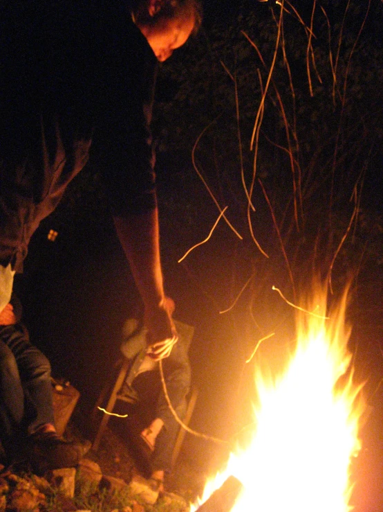 a man is cooking on a stick over fire