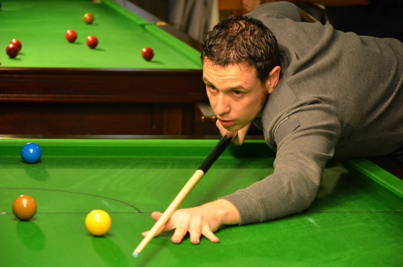 a man leaning over a pool table, holding a cue