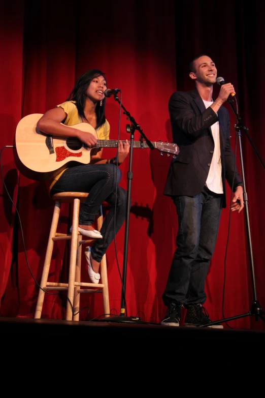 two people are singing into microphones on stage