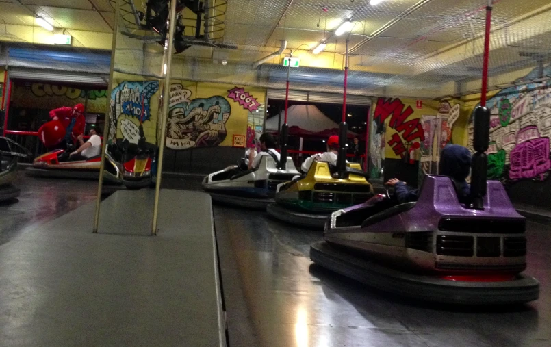 two boys ride bumper cars inside a skate park