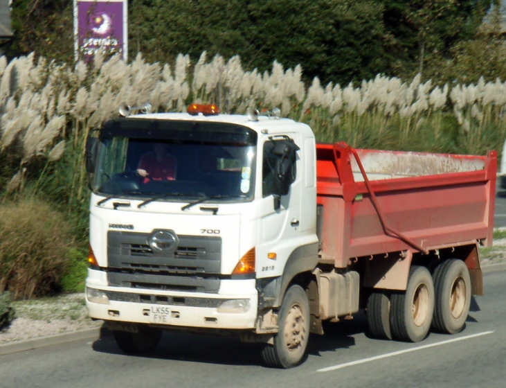 a large truck driving down a road near some tall grass