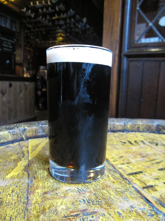 a dark beer sitting in the middle of a table