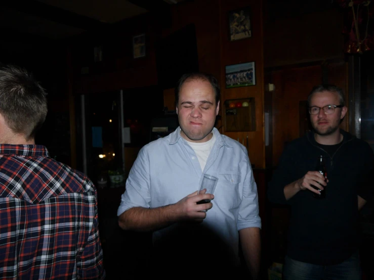 two men stand and talk in a bar