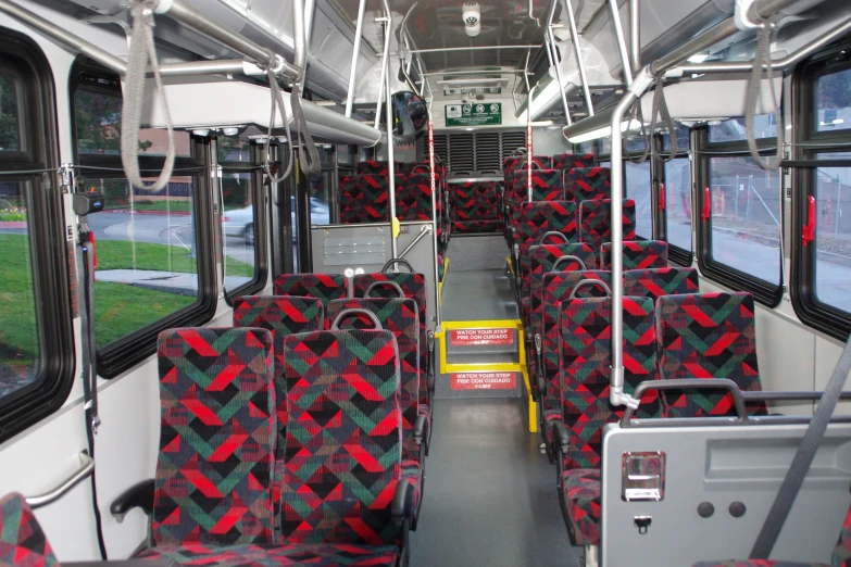 the interior of an empty bus with red and green seats