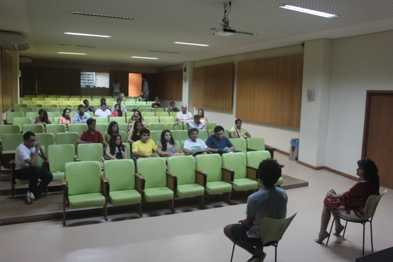 people sitting in empty auditorium seats while listening to someone speak