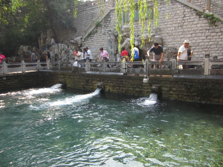 several people standing around at a small body of water