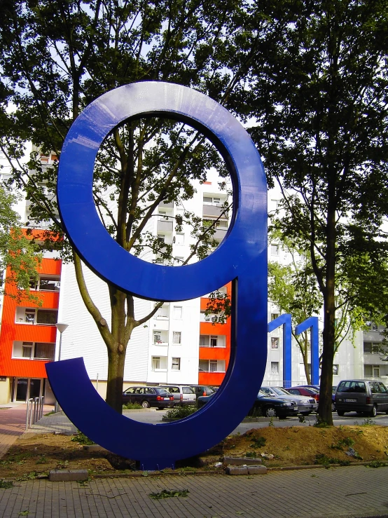 a tall blue number next to two buildings on a road