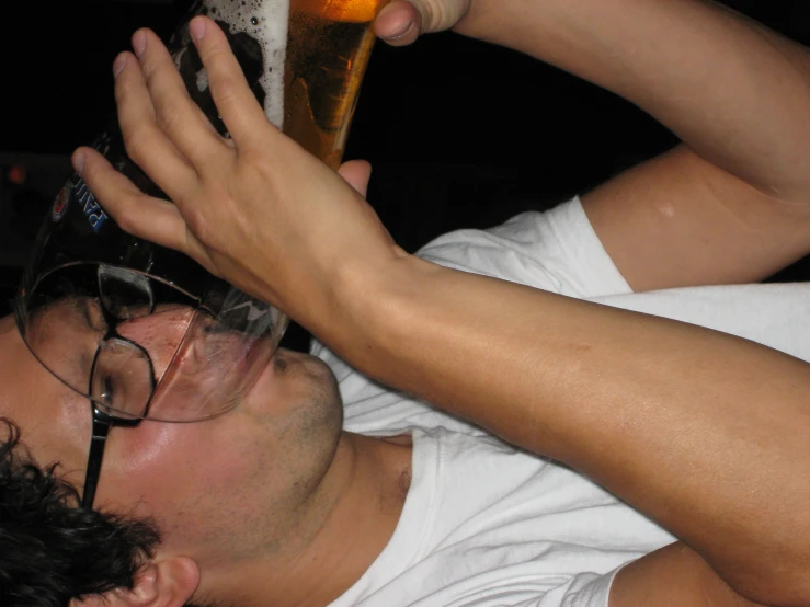a man in glasses is holding a glass of beer