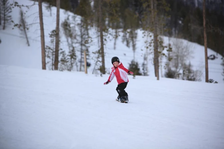 a young person riding a snow board on a snowy surface