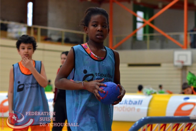 a girl in blue uniform holding a ball on the court